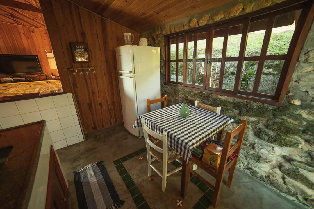 Bucătărie rustică cu masă cu față de masă în carouri și ferestre spre curte