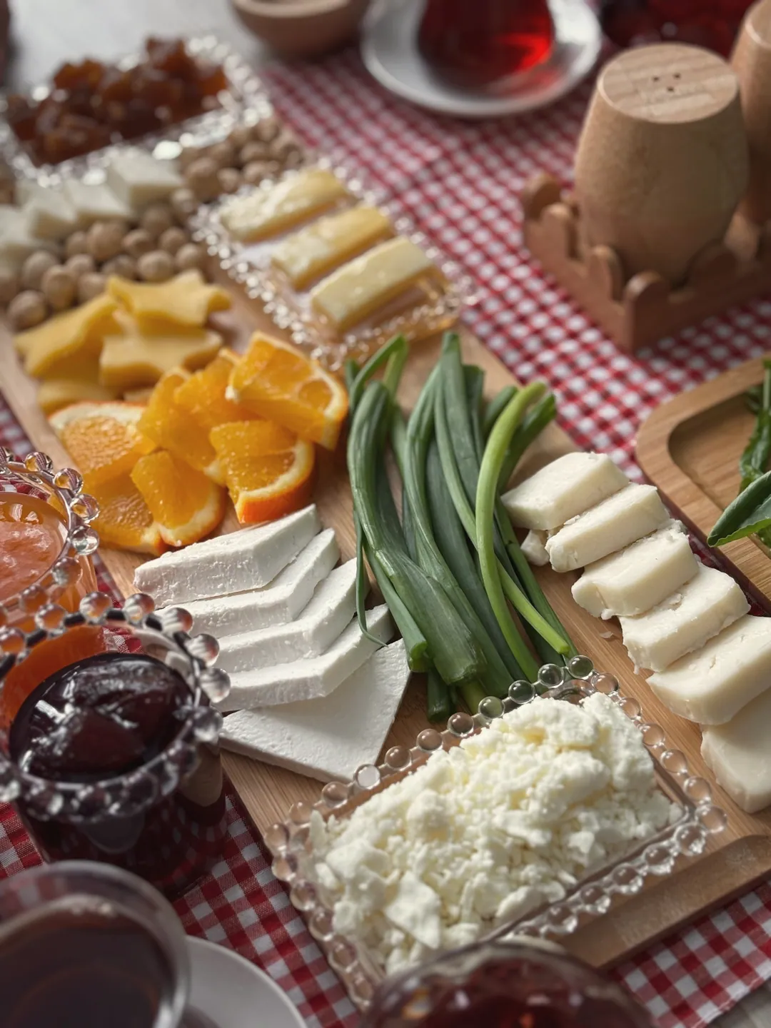 Mic dejun cu brânzeturi, legume, dulceață și pâine pe o față de masă în carouri