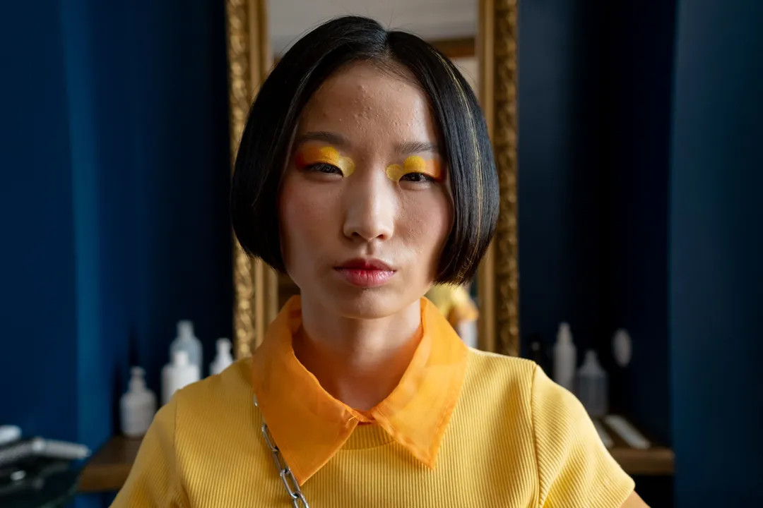 A woman with a blunt black bob in a dark blue room