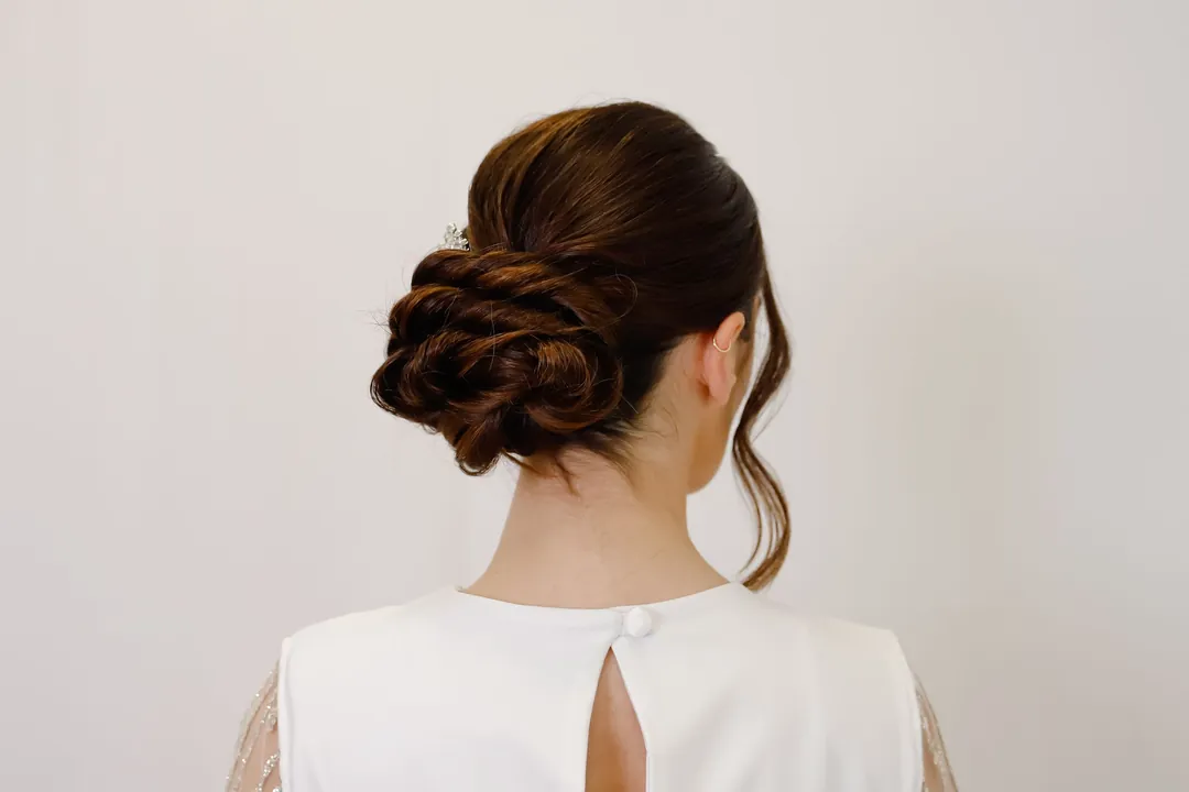 A smooth low bun with loose front pieces