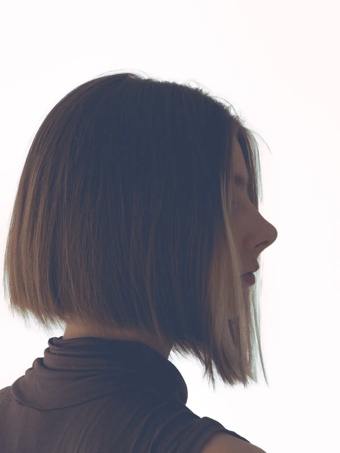 A one-length bob in profile against a white wall