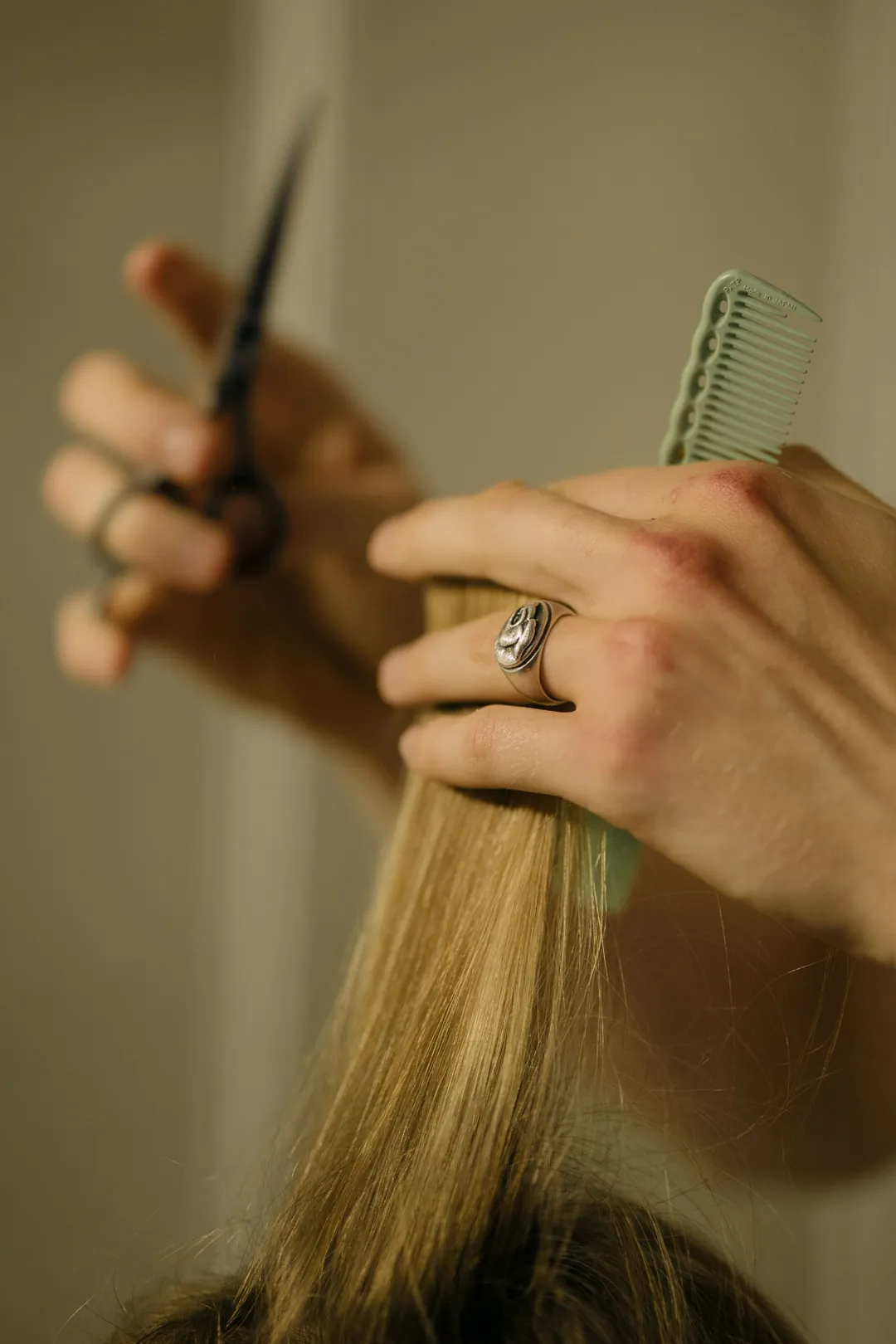 Theo at work: Scissors and a comb taking a straight line through blonde hair