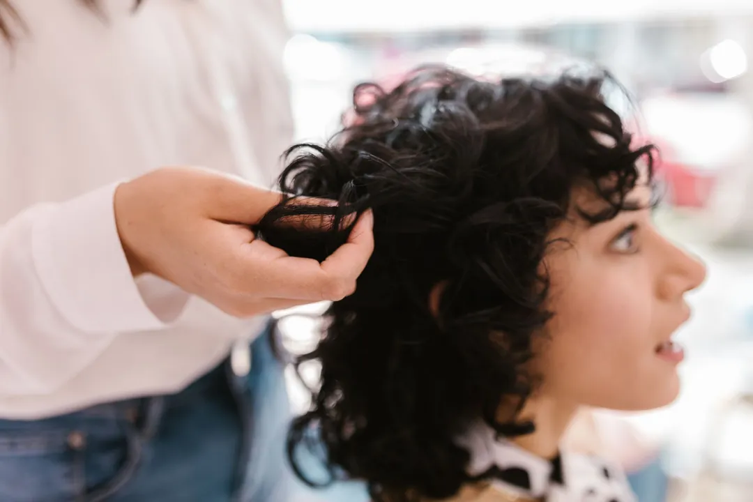 A stylist cutting dark curls with scissors