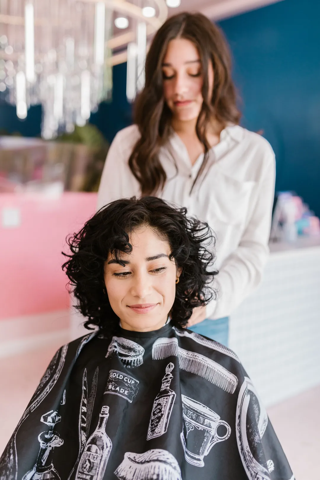 A stylist checking a client's dark curls before the cut