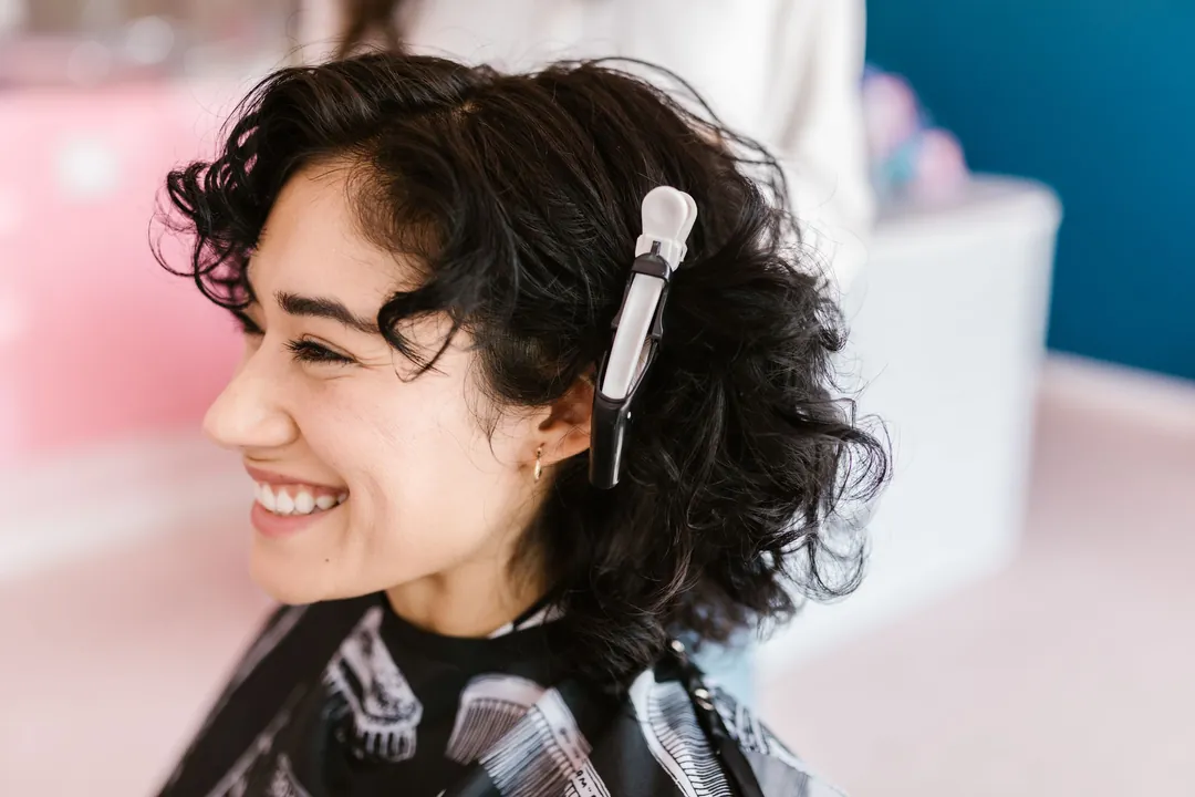 Ama at work: A client with dark curls smiling in a salon