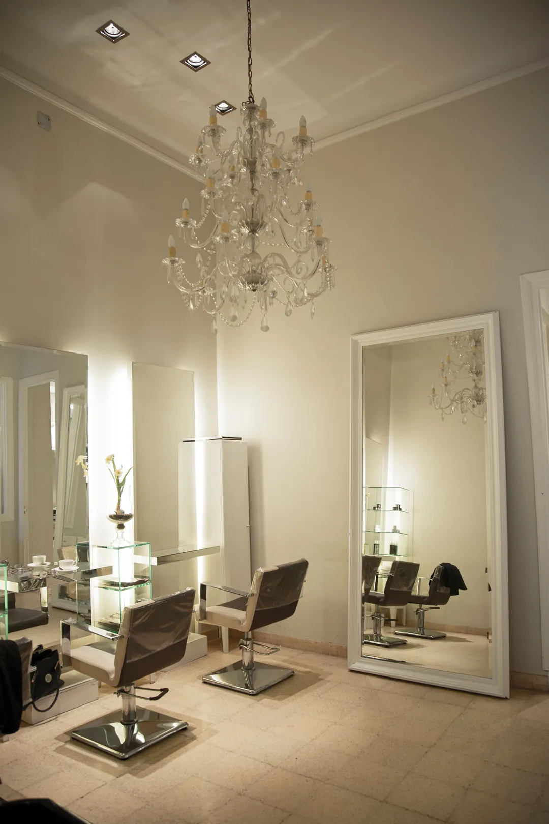 A calm cream salon with tall mirrors and a chandelier