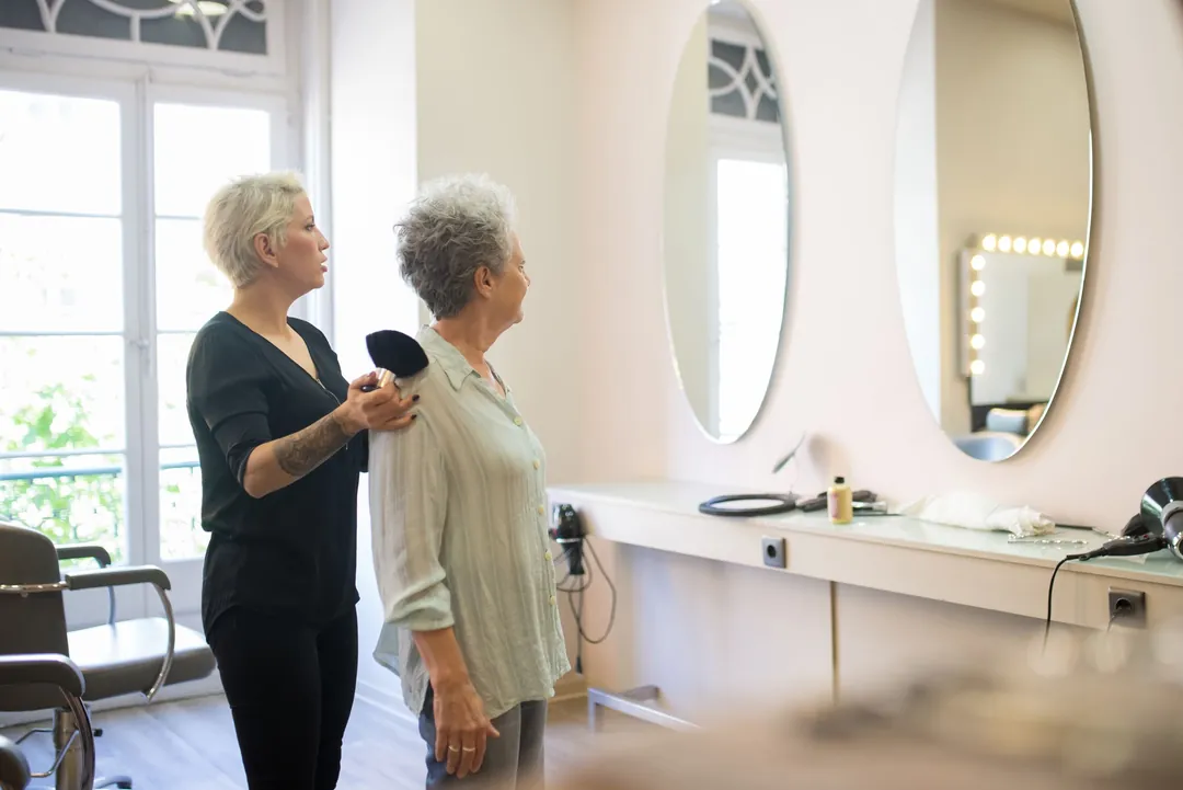 A stylist talking with a client by oval mirrors in a bright salon
