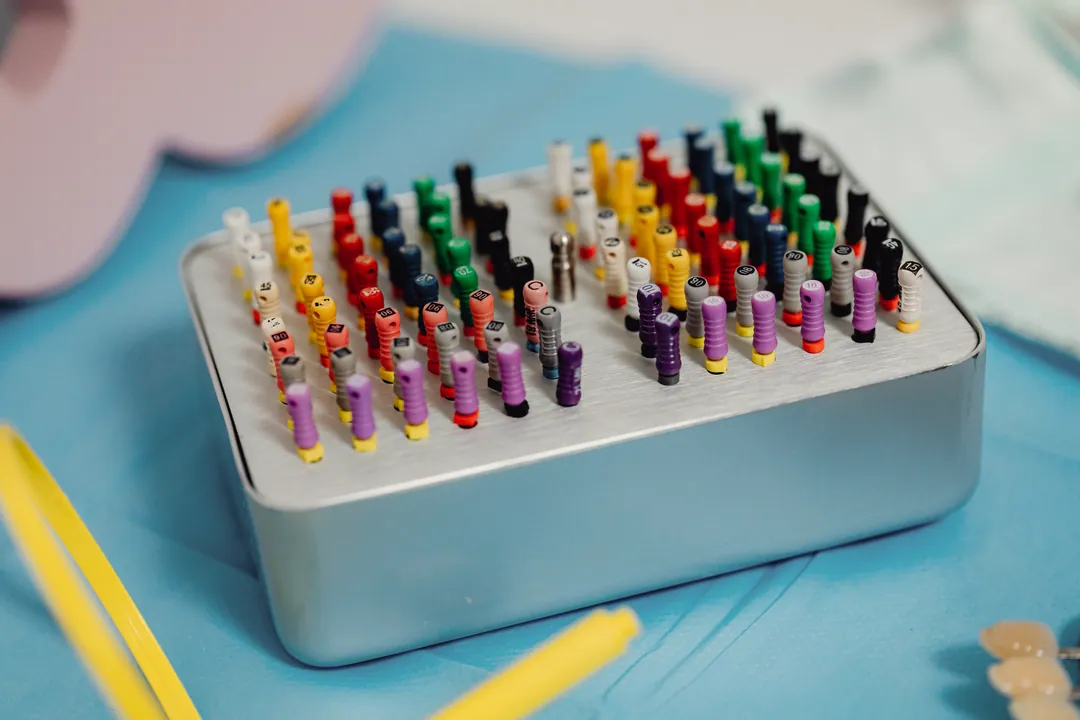 Colour-coded endodontic files stand in a steel sterilisation box