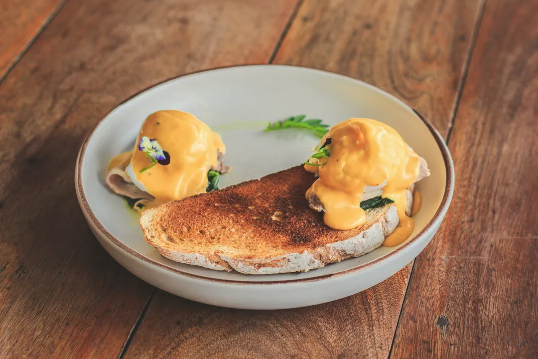 Poached eggs on toast in a shallow bowl on a wooden table