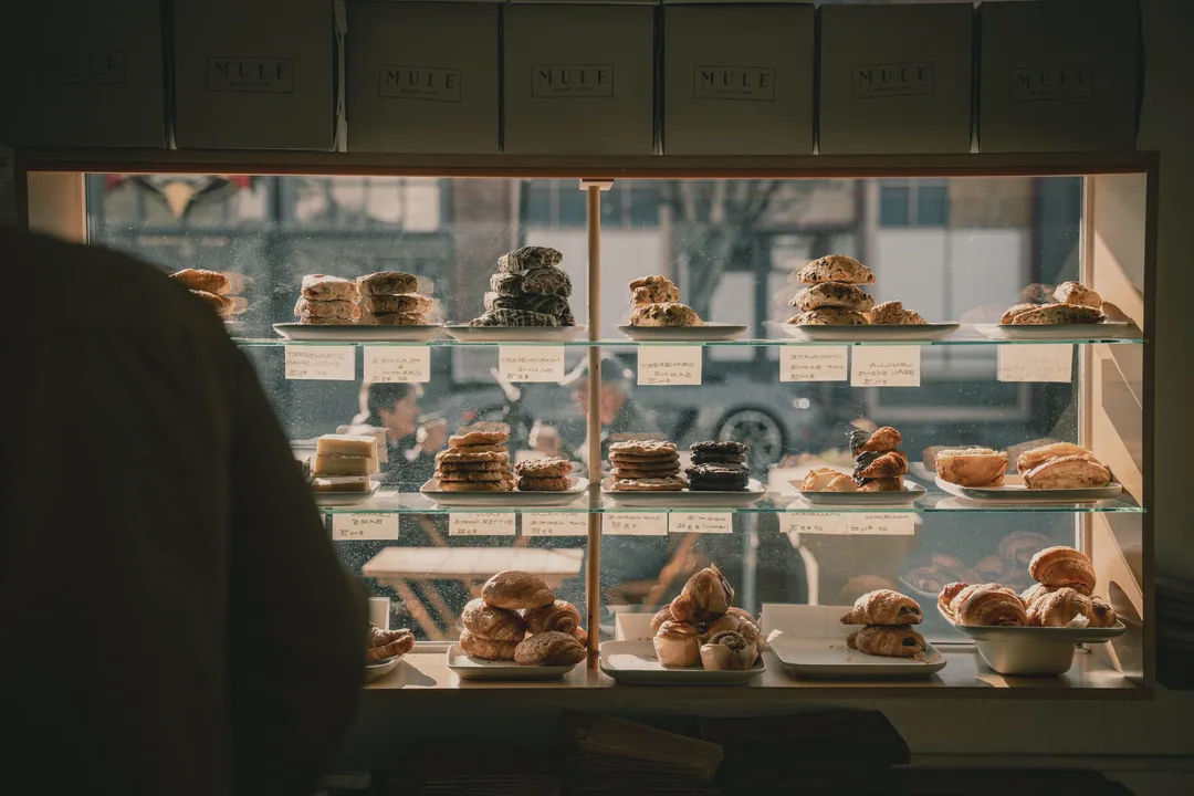 The pastry shelves seen from behind the counter, with the street through the window