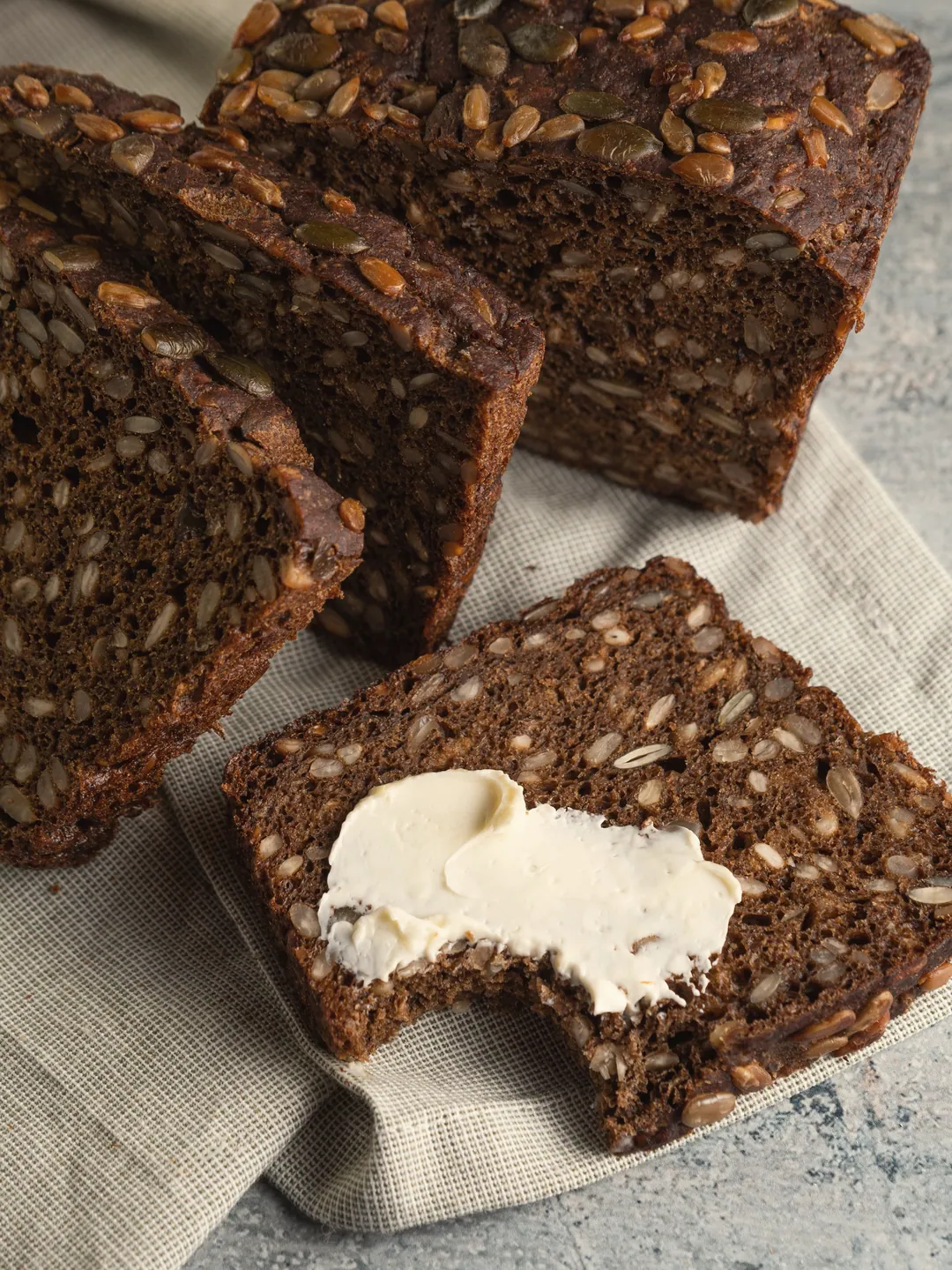 Slices of dark seeded rye, one spread with butter