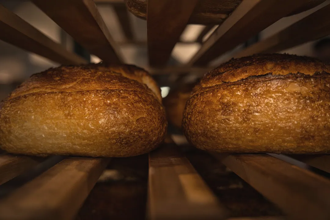 Two sourdough loaves cooling on wooden racks