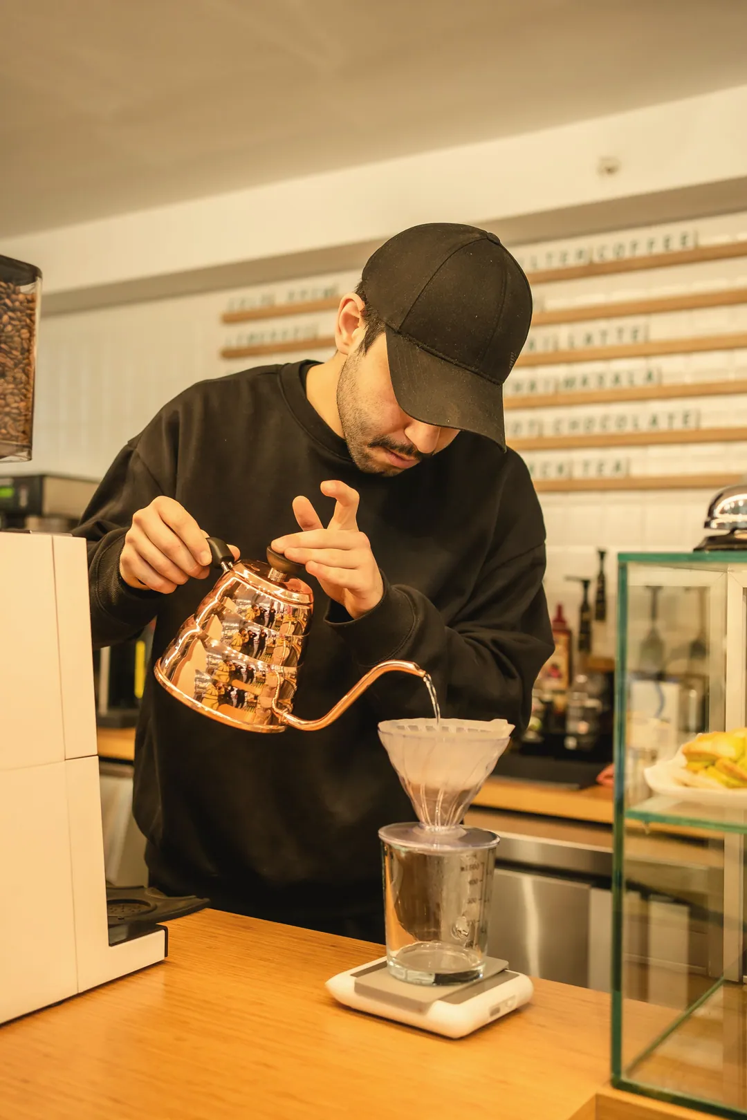A barista pouring a filter coffee from a gooseneck kettle