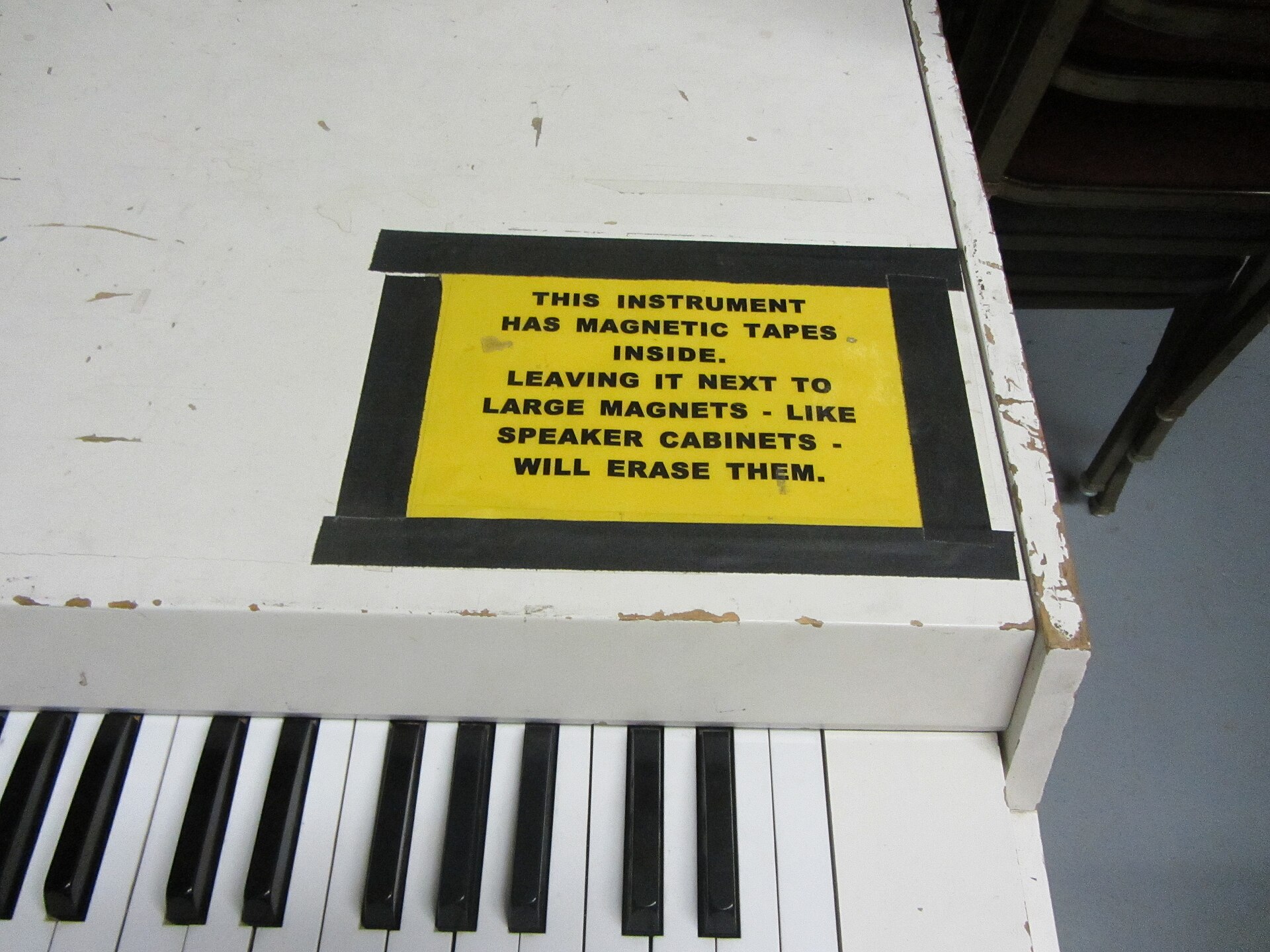 A yellow sticker on a white Mellotron warning that magnets will erase the tapes