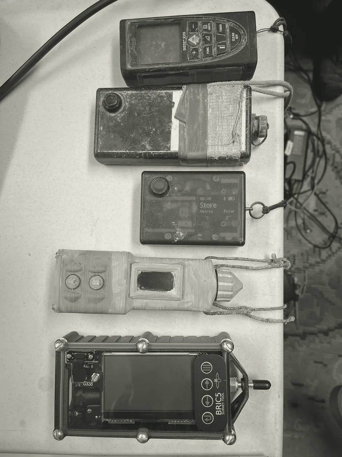 Five cave surveying instruments on a table: DistoX2, SAP2, SAP5, SAP6 and BRIC5