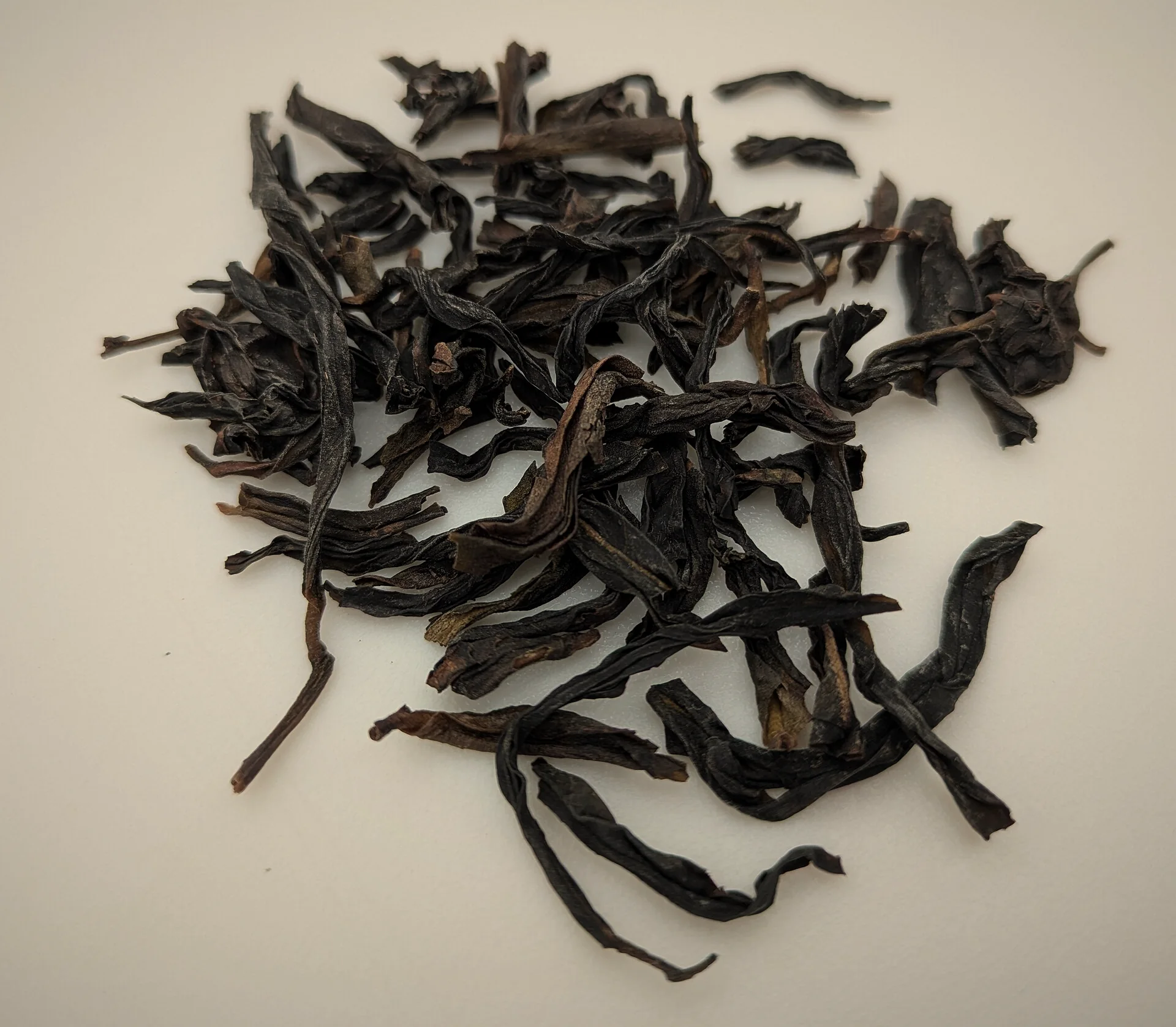 Dry Dancong oolong: long, dark, twisted leaves on a white ground