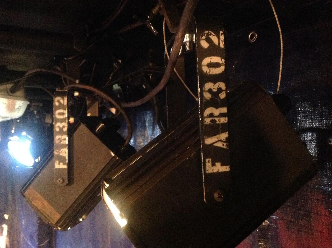 Two stage lanterns hanging from a bar, stencilled with the theatre's name