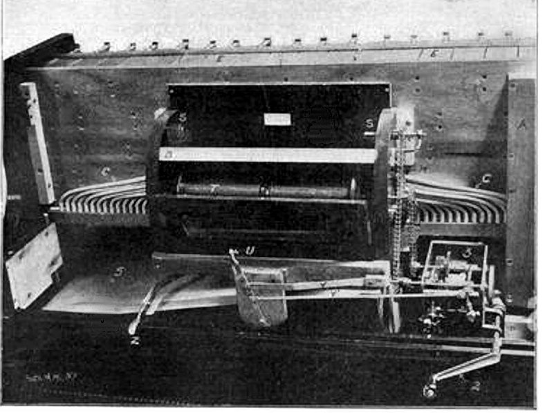 Photograph of a piano-player's works: the music roll on its spool, the winding motor, and rows of tubes running from the tracker board