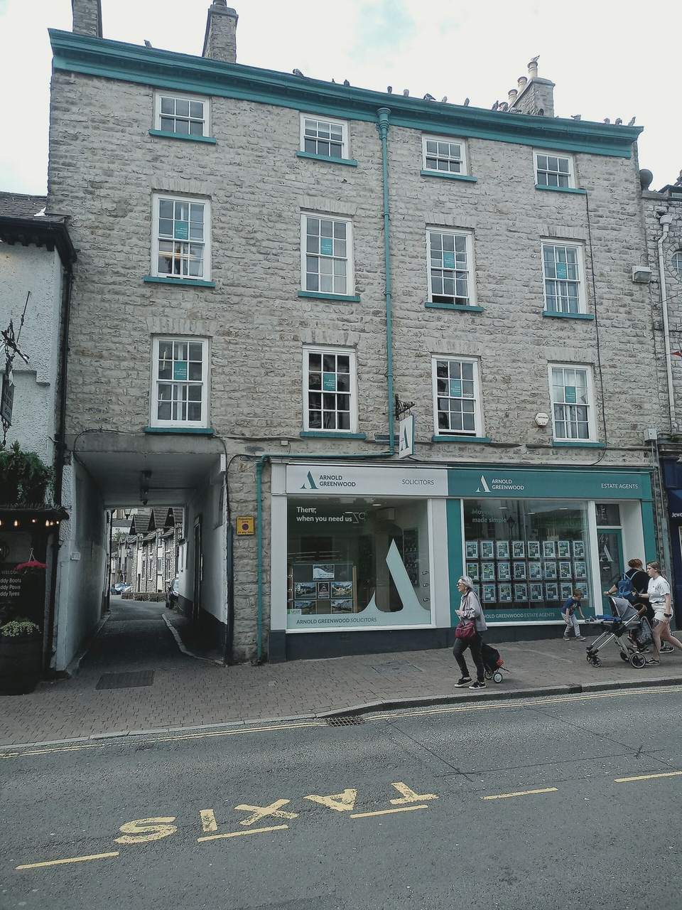 A three-storey grey limestone building on Highgate with shops on the ground floor