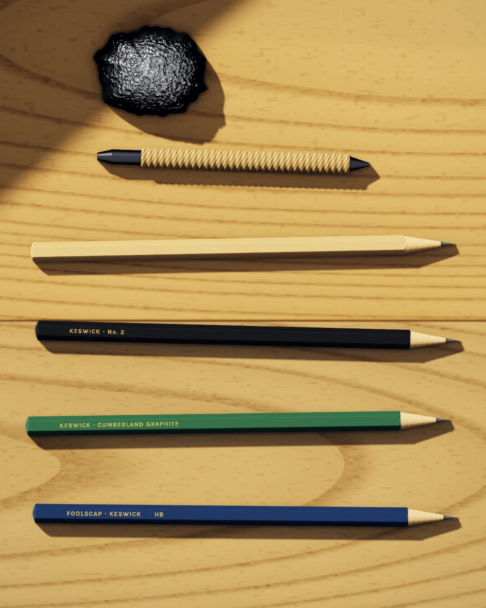 Keswick’s pencils in date order on the counter: a lump of Borrowdale graphite, a sawn stick of it bound in string, a plain cedar pencil, a black and a green lacquered pencil, and a blue Foolscap HB