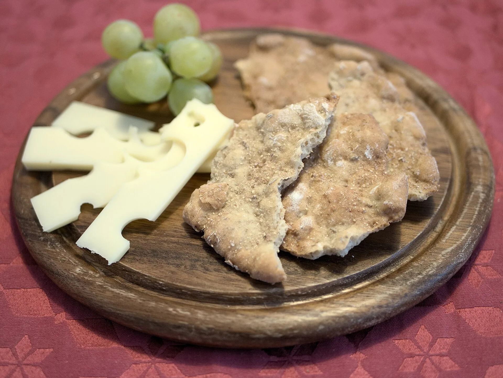 Schüttelbrot, cheese and grapes on a wooden board.