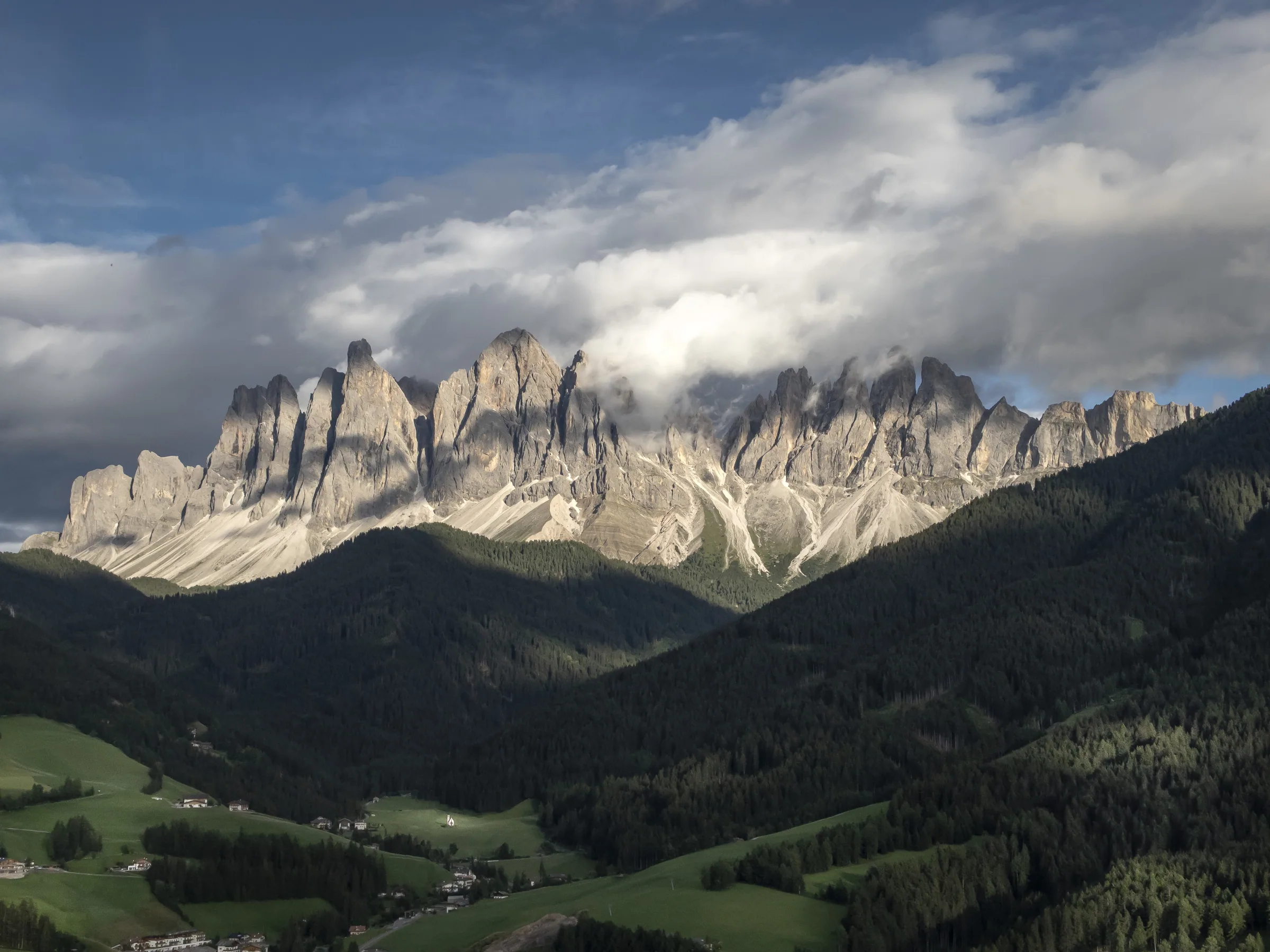 The Geisler peaks above Villnöss at sunset, the rock lit pink and the valley already in shadow.
