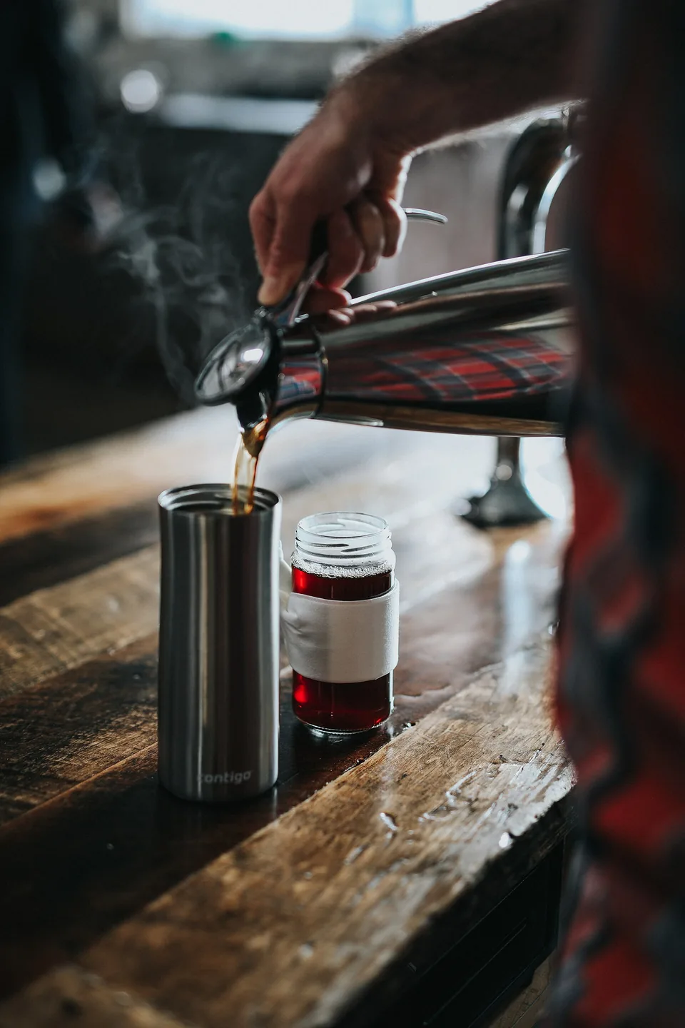 A bartender pouring from a shaker into a glass on a wooden bar