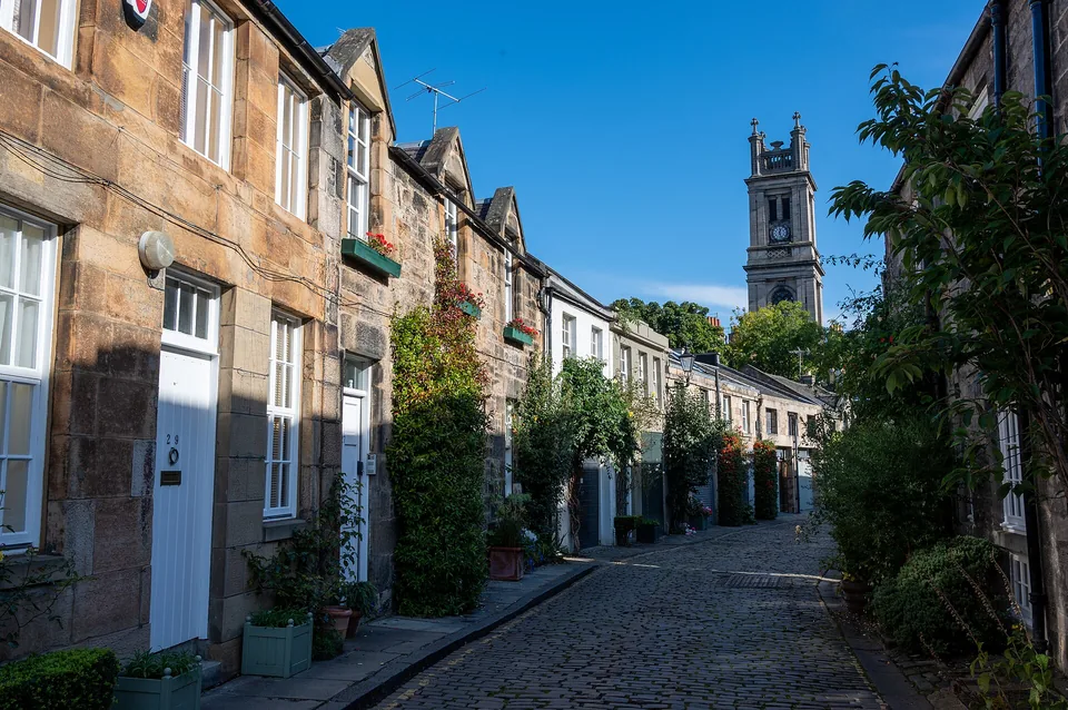 Circus Lane in Stockbridge: a curving cobbled mews with ivy, the tower of St Stephen’s at its end