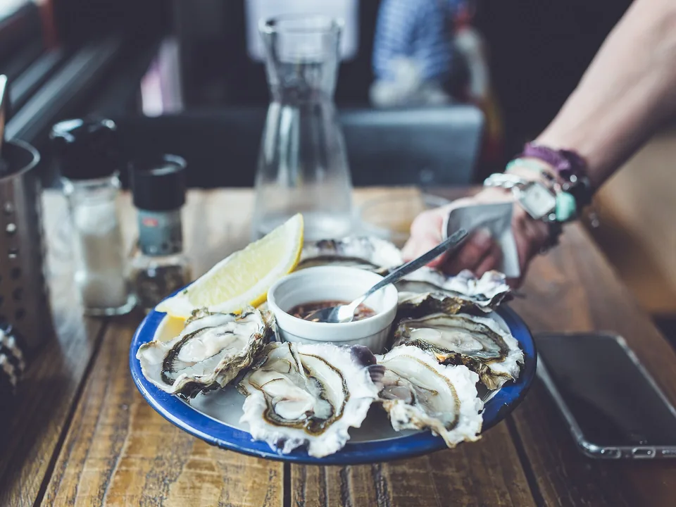 A plate of oysters with lemon and a dish of shallot vinegar on a bar