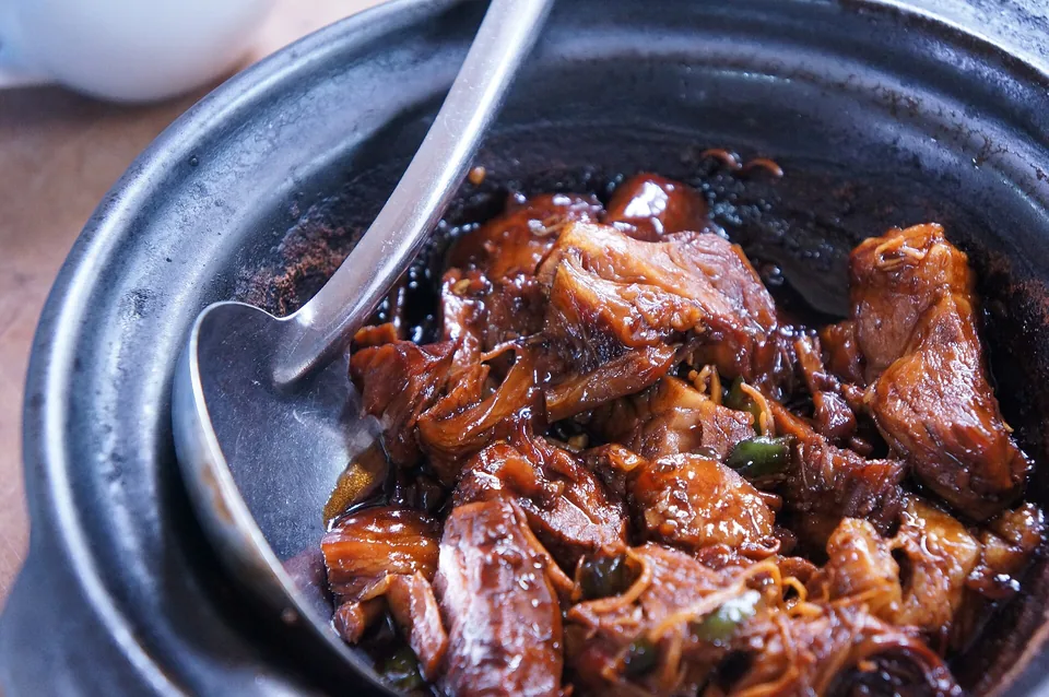 A dark braise in a cast-iron pot with a spoon