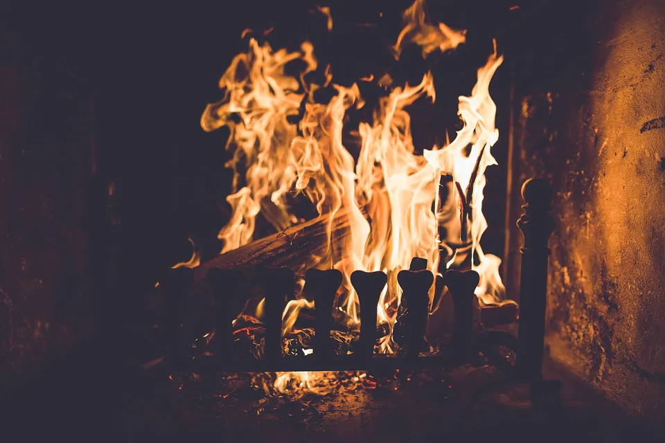 Logs burning high in an iron grate in a stone fireplace