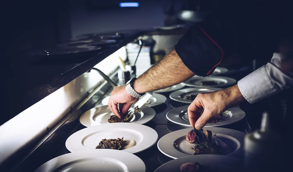 A cook plating small dishes along a steel pass