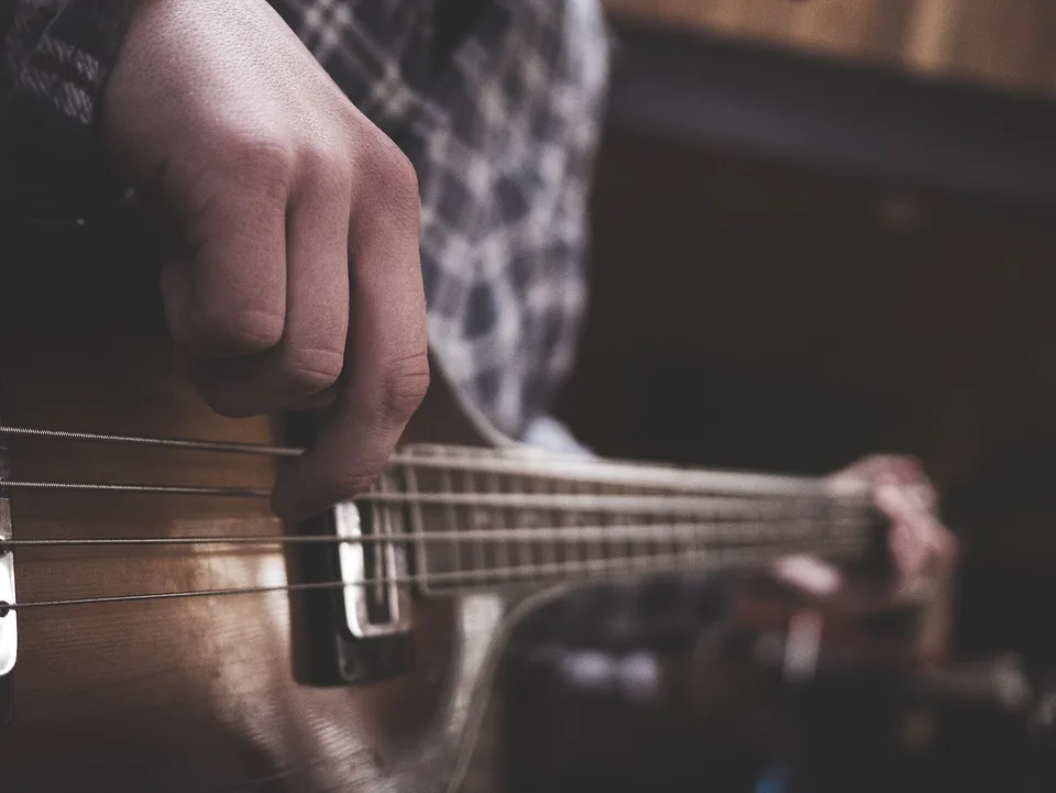 Close up of hands on an electric bass in a dark room
