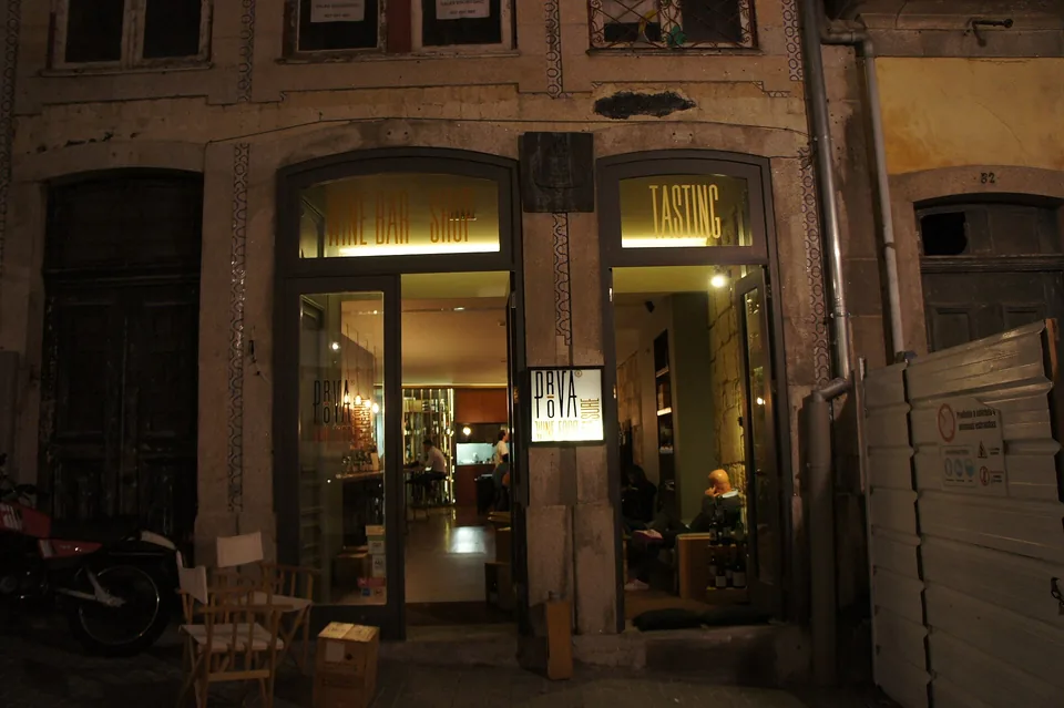 A stone shop front at night, its door and windows lit from inside