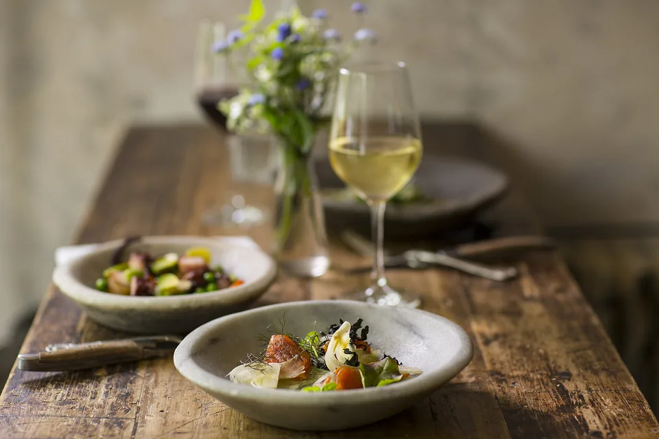 Two small plates and a glass of white wine on an old wooden table