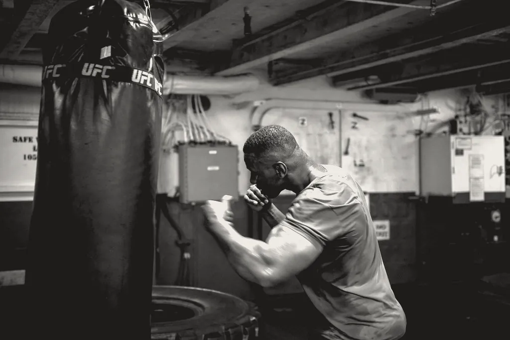 A boxer working a heavy bag in a dark room, guard up.