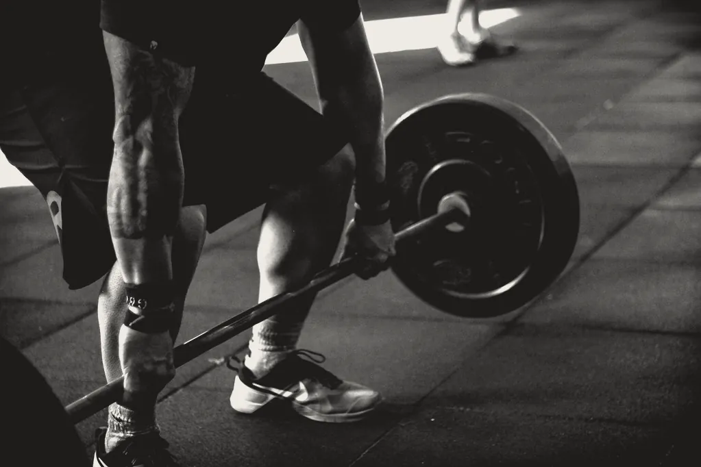 A lifter set up for a deadlift: hands on the bar, shins close to it, the plate on the floor.