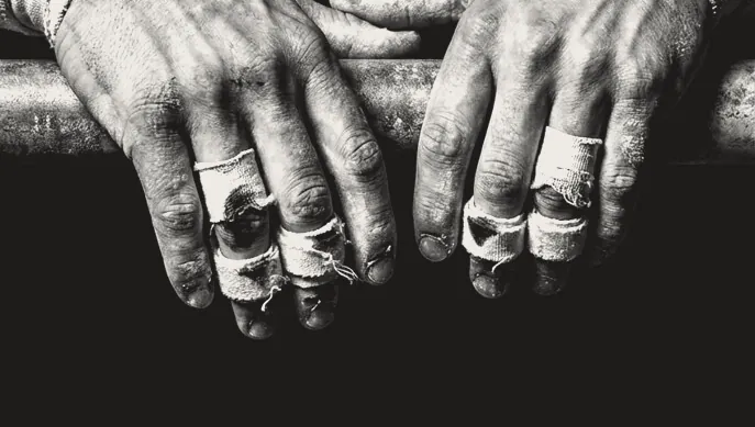 Taped, chalked hands resting on a barbell between sets.
