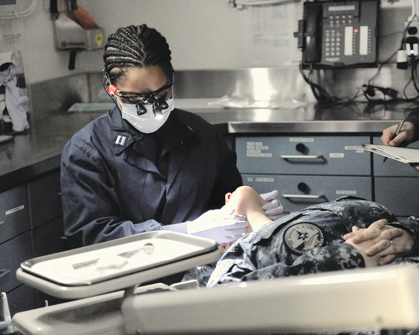Dr. Clara Hale examining a patient under magnifying loupes