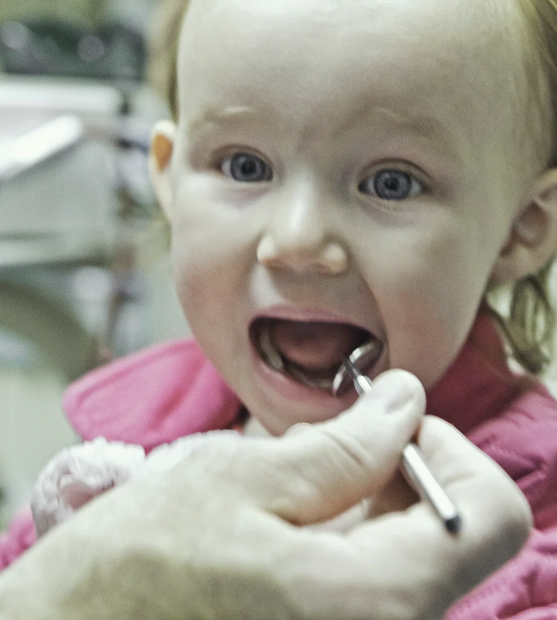 A toddler at her first check-up, mouth open for the mirror