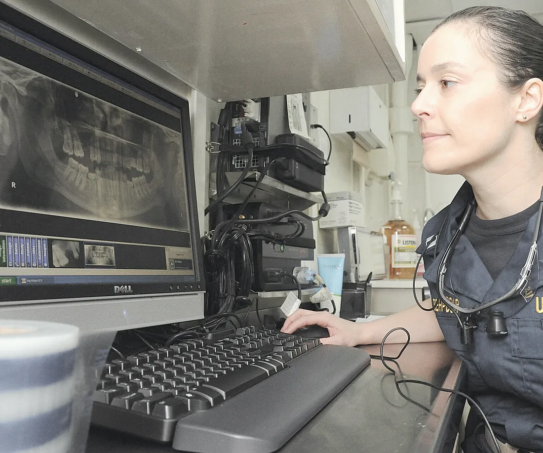 A dentist reading a full-mouth X-ray on the screen