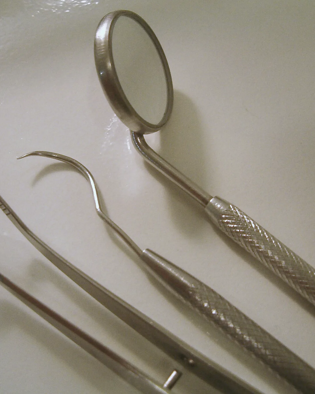 A mouth mirror, probe and tweezers in warm light