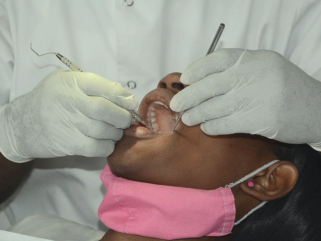 Gloved hands using a mirror and a scaler during a clean