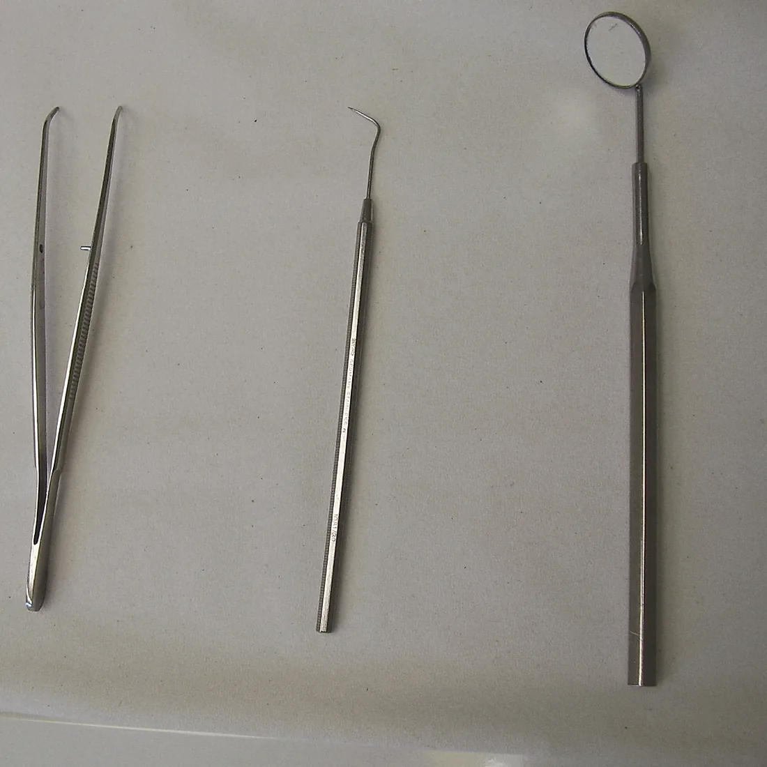 Tweezers, a probe and a mouth mirror, the three instruments of every check-up