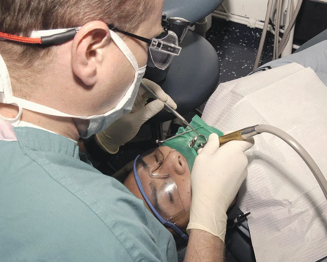 Dr. Tomás Ferreira working with loupes and a rubber dam