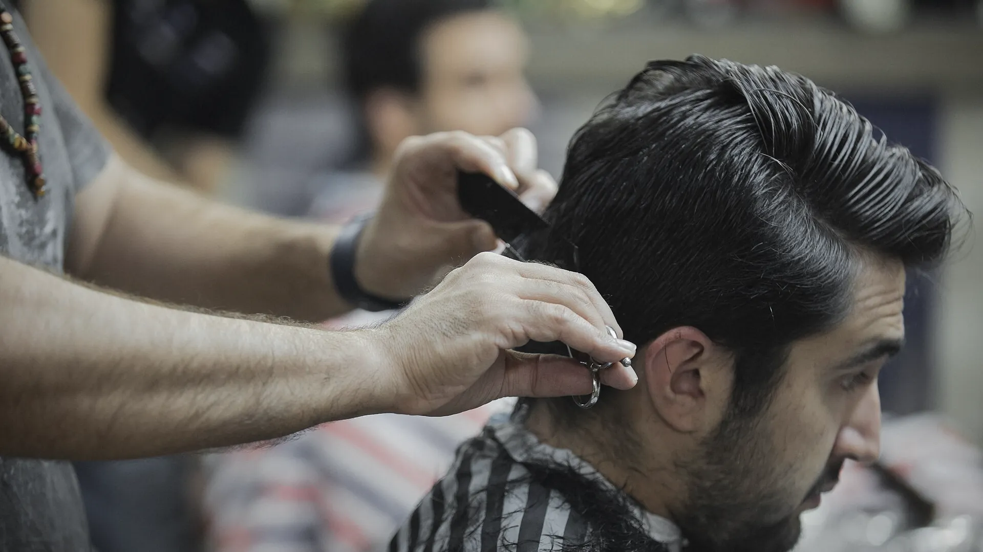 Scissors over comb behind the ear on a side-parted haircut