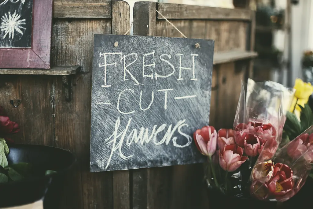 A chalkboard sign reading Fresh cut flowers beside buckets of tulips