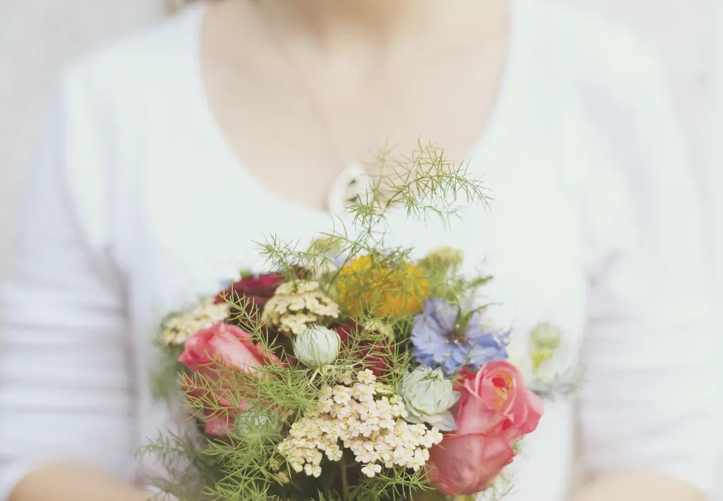 A small hand-tied posy of pink roses, yarrow and cornflowers