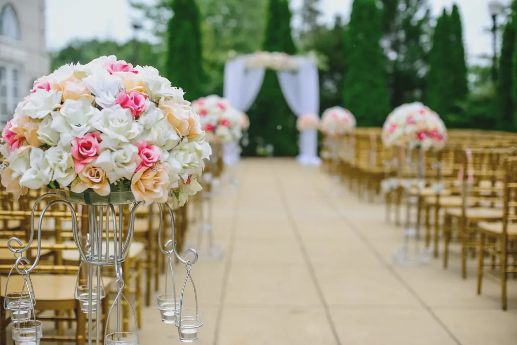 A wedding aisle lined with tall arrangements of pink and white roses