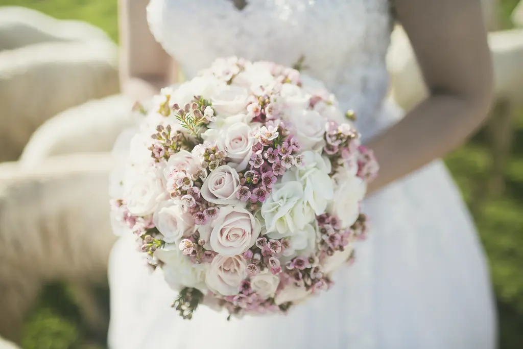 A round bridal bouquet of dusky pink roses and wax flower